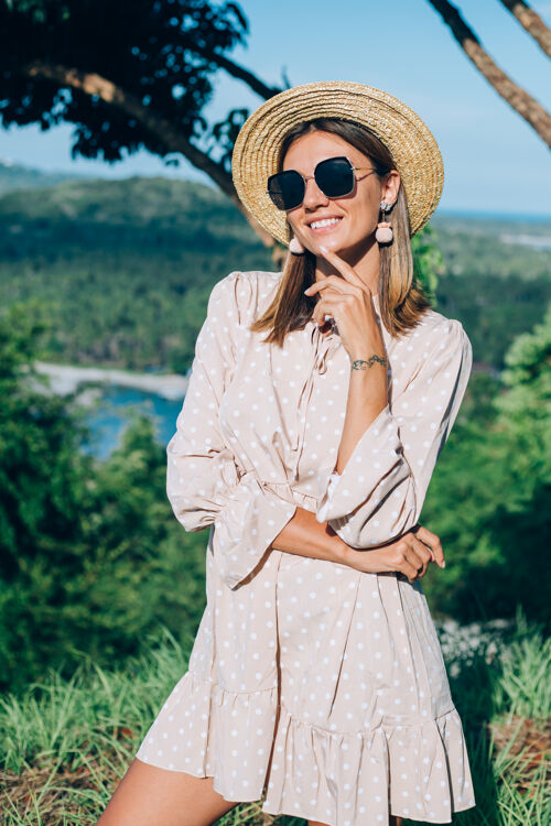 年轻穿着夏装 戴着太阳镜和草帽的年轻快乐女人的肖像时尚异国情调配饰