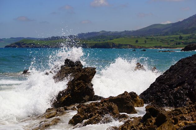 能量海浪拍打着岩石 后面是蓝色的海洋岩石波浪海岸