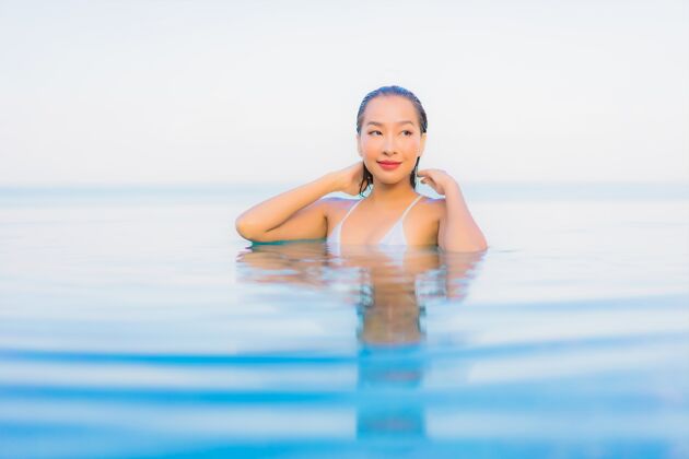 健康肖像美丽的亚洲年轻女子放松微笑周围的室外游泳池在酒店度假村放松豪华海滩