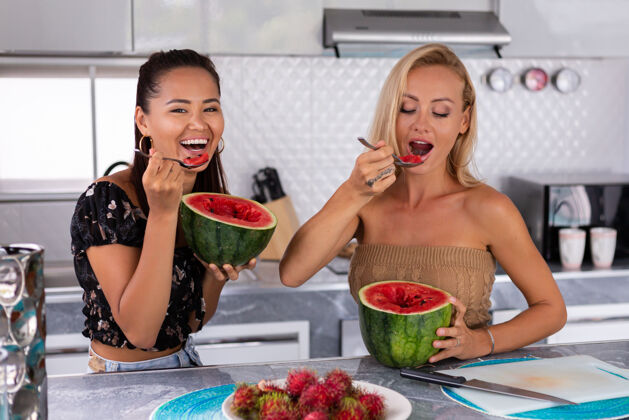 家两个女朋友在厨房吃西瓜和红毛丹热带水果吃食物有机