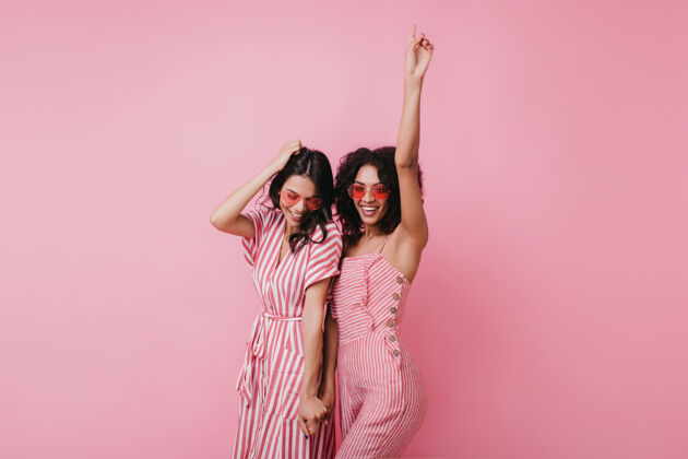 乐趣性感的非洲女士和她最好的朋友在一起玩穿着粉色衣服的可爱女孩站在室内的照片模特微笑可爱