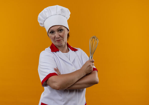 自信自信的中年女厨师身着厨师制服 双手交叉握着威士忌 孤零零地站在黄色的墙上交叉制服厨师