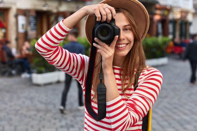 帽子快乐的女性在业余时间花在业余爱好上 在闲暇时用相机拍摄城市街道高兴头饰服装