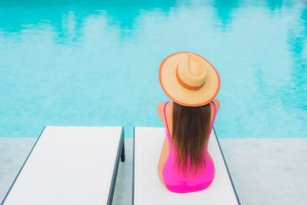 泳装肖像美丽的亚洲年轻女子放松微笑周围的室外游泳池在酒店度假村水度假村休息