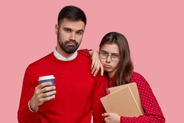 男性劳累过度的女人和男人都有悲伤的表情 拿着笔记本 外卖咖啡 穿着红色衣服同学书呆子悲伤