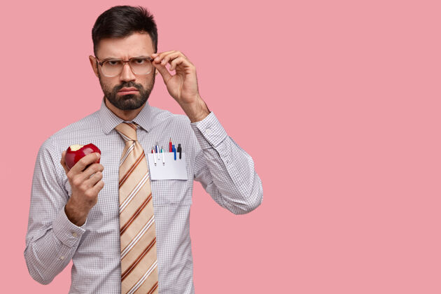 经理严肃忧郁的男老板穿着正装 手戴眼镜 咬着美味的红苹果员工胡茬男性