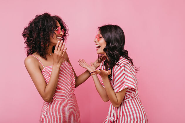 欢快有趣的故事让两个朋友开怀大笑穿着粉色条纹衣服的女孩们正在玩的画像成人放松人