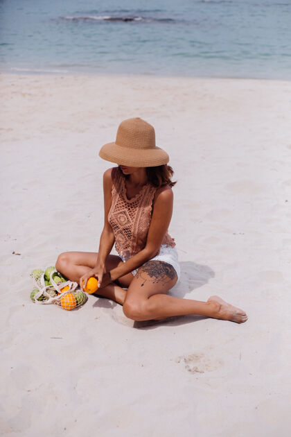 服装年轻漂亮的白种人 皮肤黝黑 穿着针织衣服 戴着帽子在沙滩上上衣套装棕色