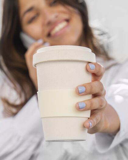 流行病微笑的女人一边拿着咖啡杯一边打电话疾病大流行新