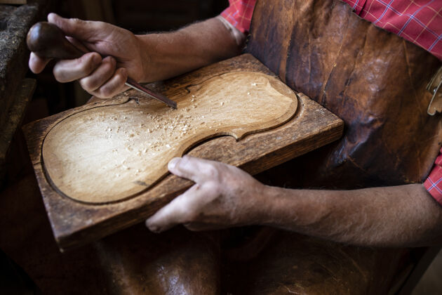 人木匠的手在他的旧时装工作室里塑造和雕刻木头的特写镜头手工刨花工作