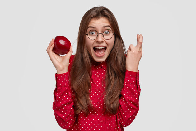 愿望喜极而泣的女士举手合十 祈求好运 捧着新鲜的苹果 享受健康的营养 穿着红色的衣服果汁积极有机