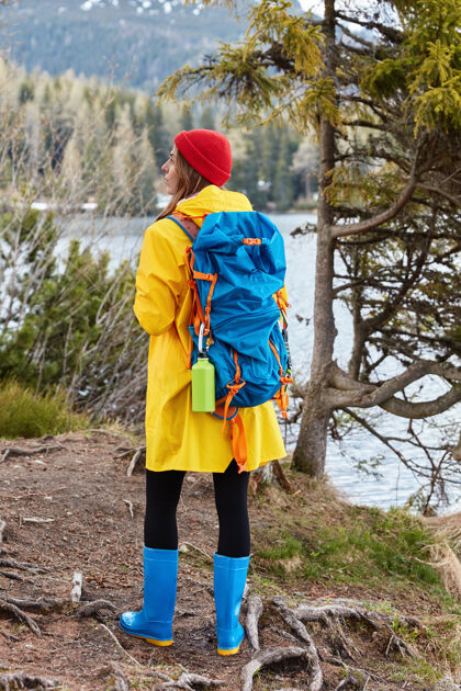 散步活动中的女徒步者站在山湖附近的山上 戴着红帽子 这是一个完整的镜头照片远足背包