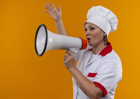 扩音器看着旁边穿着厨师制服的中年女厨师在喇叭上讲话 在隔离的黄色墙上举手女制服厨师