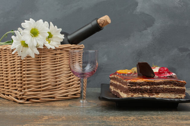 甜的美味的蛋糕和篮子和瓶子放在大理石桌上黑的瓶子蛋糕