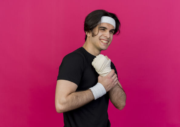 戴着一个穿着运动服 戴着头巾的年轻人微笑着抚摸着他缠着绷带的手腕触摸手腕粉色