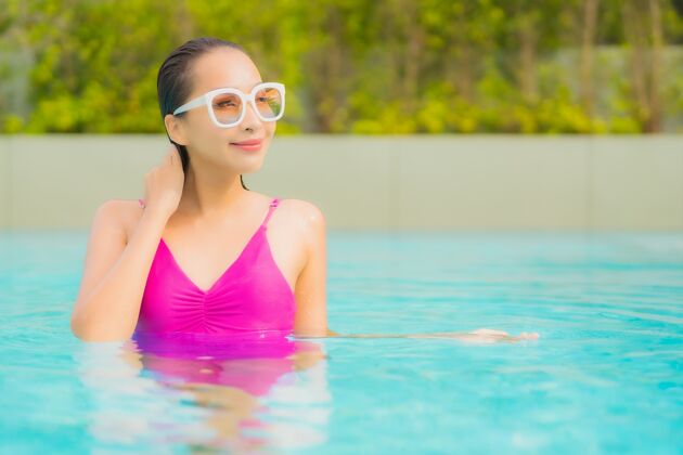 游泳肖像美丽的亚洲年轻女子放松微笑周围的室外游泳池在酒店度假村游泳池热休闲