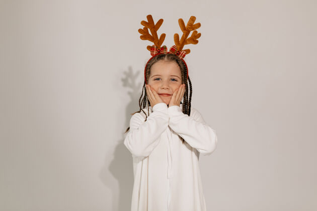 季节有趣迷人的女孩在圣诞快乐心情圣诞帽鹿角兴奋摆姿势