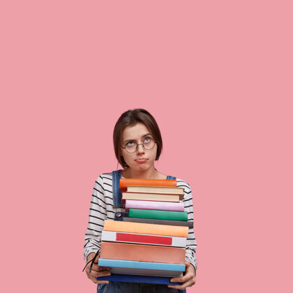 沉思沉思不满足的女士拿着成堆的书 戴着眼镜眼镜读者书房