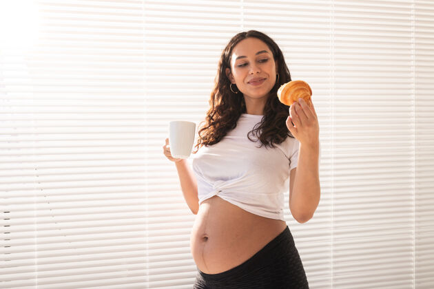 休息快乐孕妇在家吃羊角包怀孕和人的概念不健康室内微笑